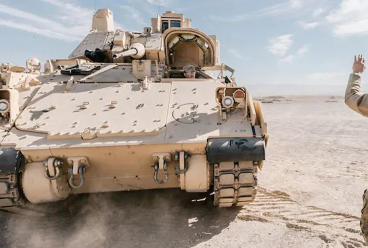 a soldier waves to a tank in the desert